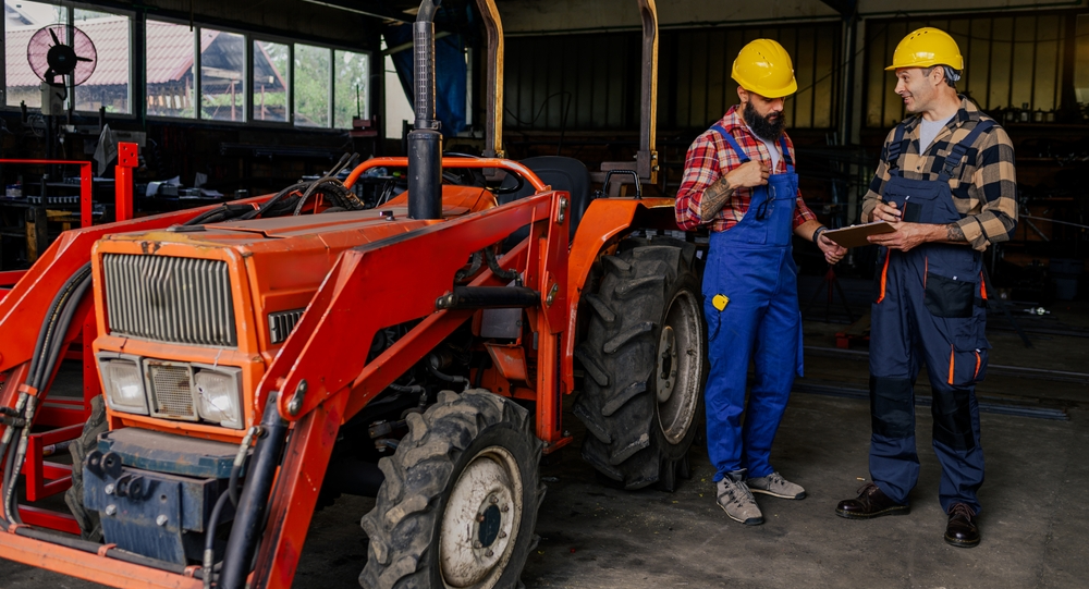 Dva farmáři stojí ve stáji u červeného traktoru